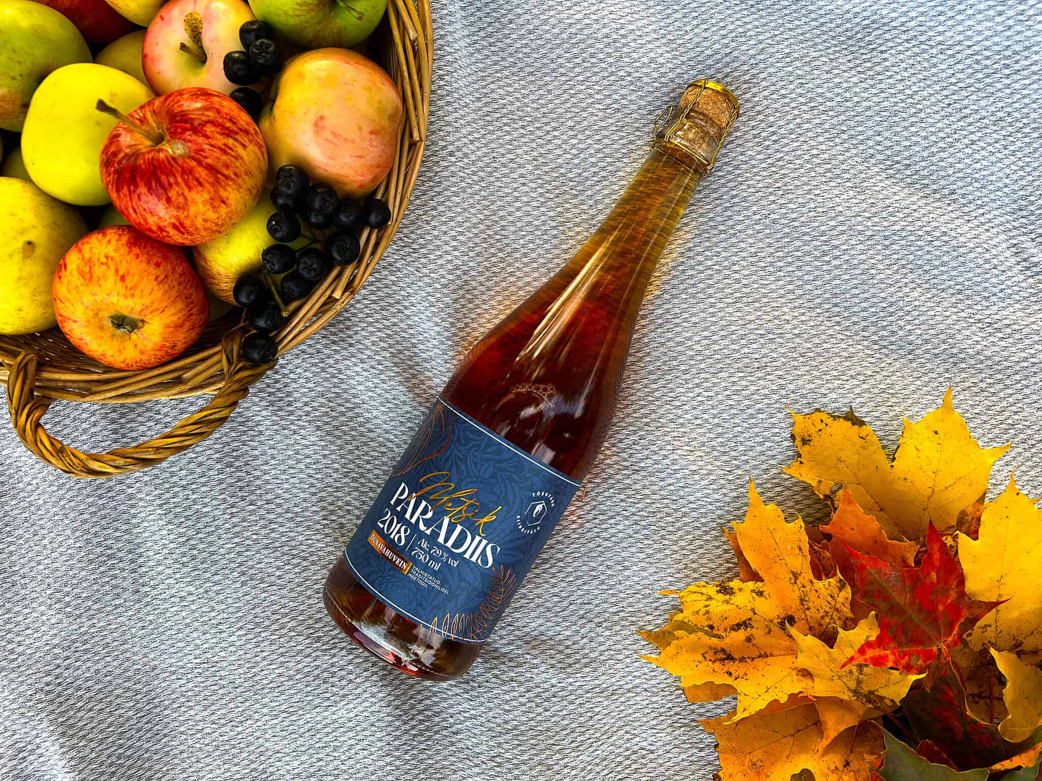 Metsik Paradiis vahuvein piknikulinal koos õunakorvi koos arooniate ja vahtralehtedega.